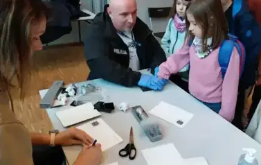 Warsztaty z daktyloskopii - uczniowie odbijają odciski swoich dłoni.