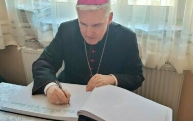 Biskup dokonuje pamiątkowego wpisu do kroniki