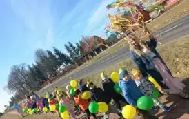 Dzieci idą z balonami i wiosennym gaikiem.