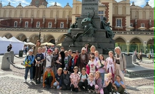 Zdjęcie grupowe uczniów klas I–III przy pomniku Adama Mickiewicza w Krakowie